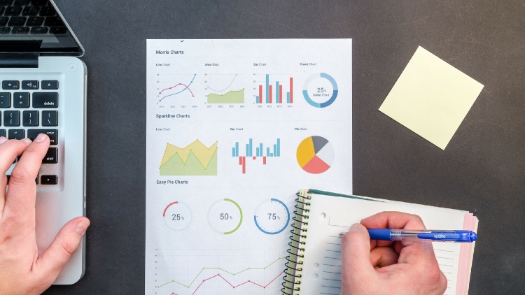 Personne qui travaille sur une feuille avec des chiffres et des graphiques