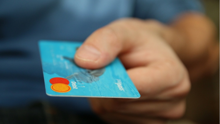 Gros plan sur la main d'un homme qui tend sa carte bancaire