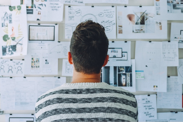 Personne de dos qui consulte une planche de tendances sur un tableau