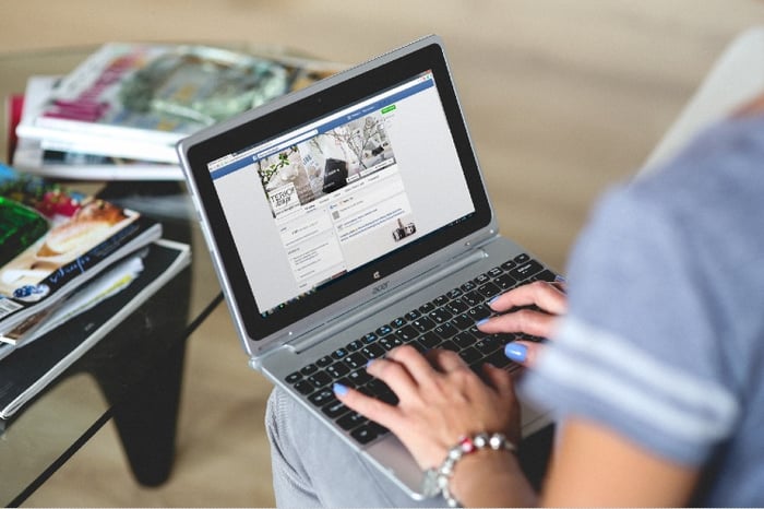 Femme qui consulte une page Facebook sur un ordinateur portable